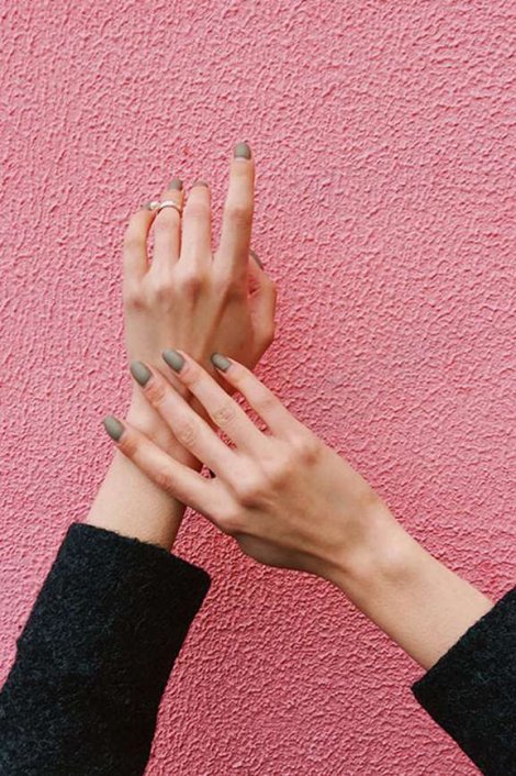Frauenhände vor einer pinkfarbenen Wand.