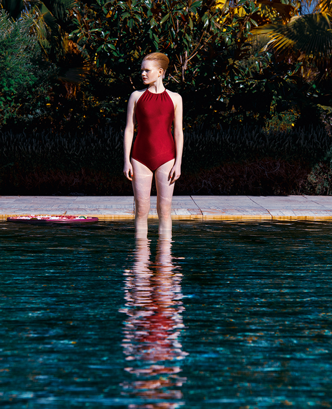 After Sun: Frau im Badeanzug steht im flachen Poolwasser.