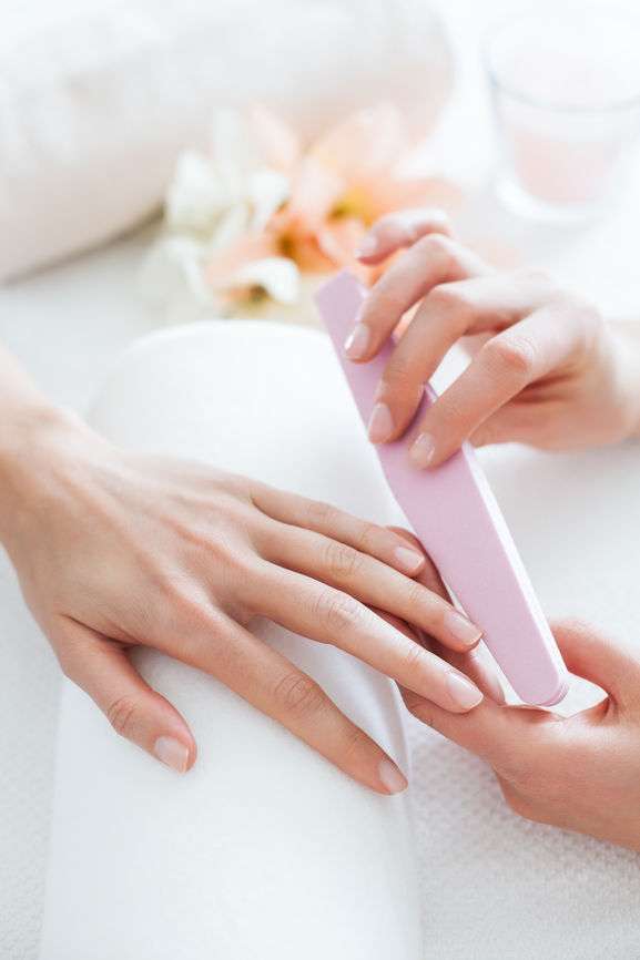 Hände einer Frau und einer Kosmetikerin bei der Nagelpflege