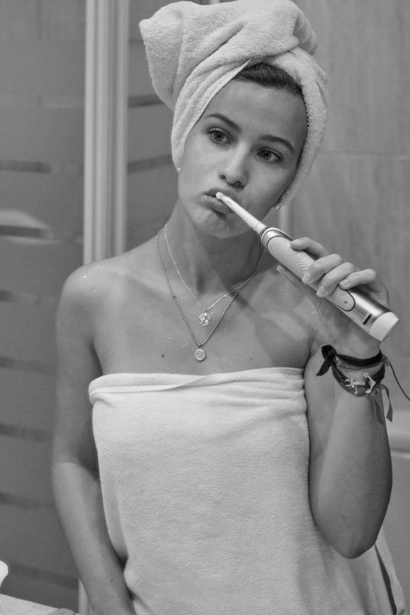 Frau putzt sich mit einer elektrischen Zahnbürste die Zähne.