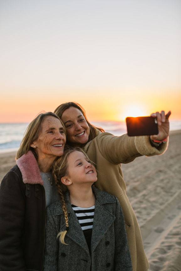 Drei Generationen: Mutter, Tochter und Kind, die am Stand ein Selfie machen