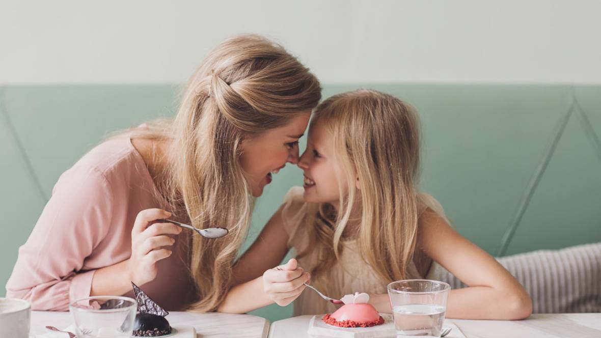 Eine Mutter mit ihrer Tochter, die ihr Dessert genießen und sich anstrahlen.