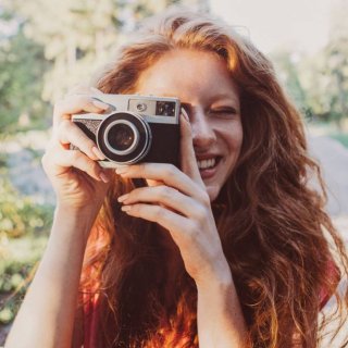 Frau mit langen, roten Haaren macht schöne Bilder mit Vintagekamera