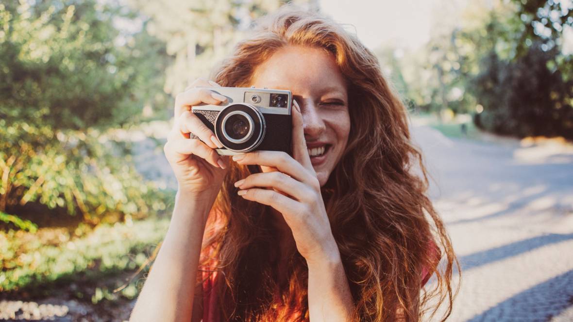 Frau mit langen, roten Haaren macht schöne Bilder mit Vintagekamera