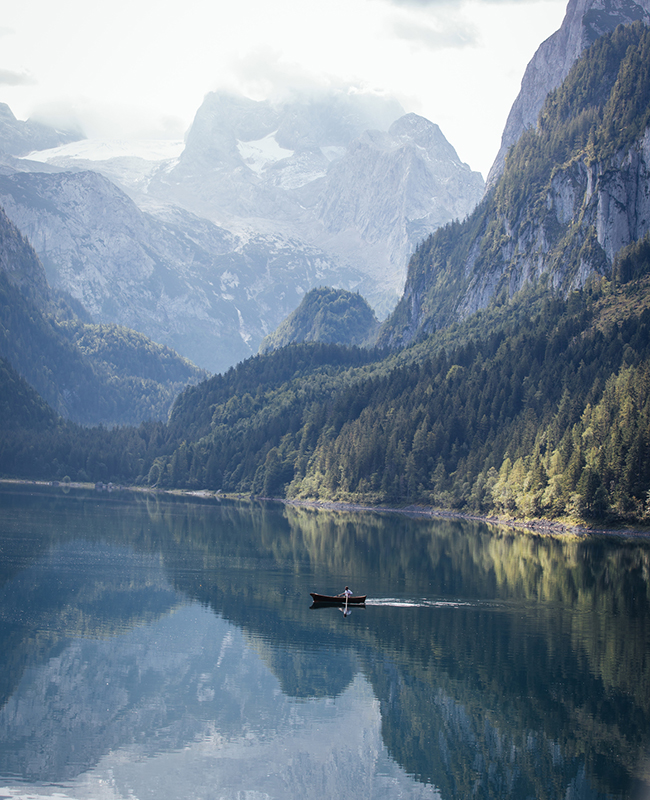 Stiller See vor Bergkulisse mit einsamen Ruderboot, etwa in den Sommerferien 2020 zuhause in Österreich
