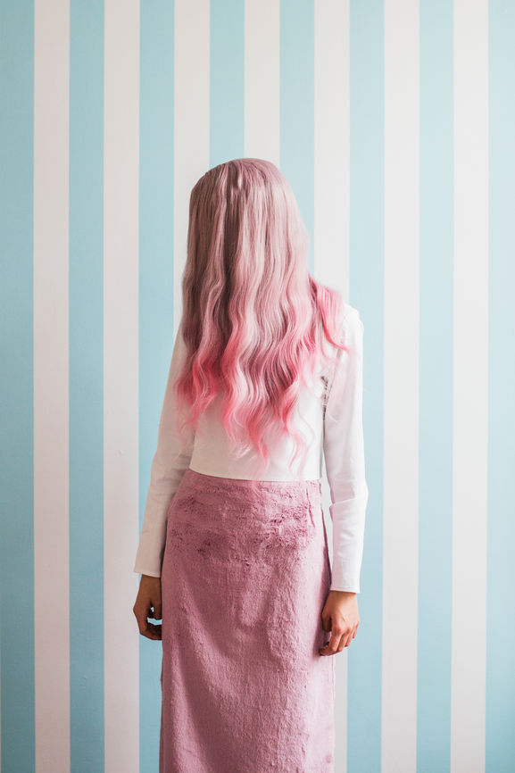 Frau mit langen rosa Haaren vor dem Gesicht