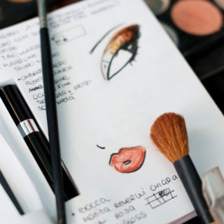 Skizzenbuch mit Make-up-Look, auf dem Make-up-Pinsel liegen