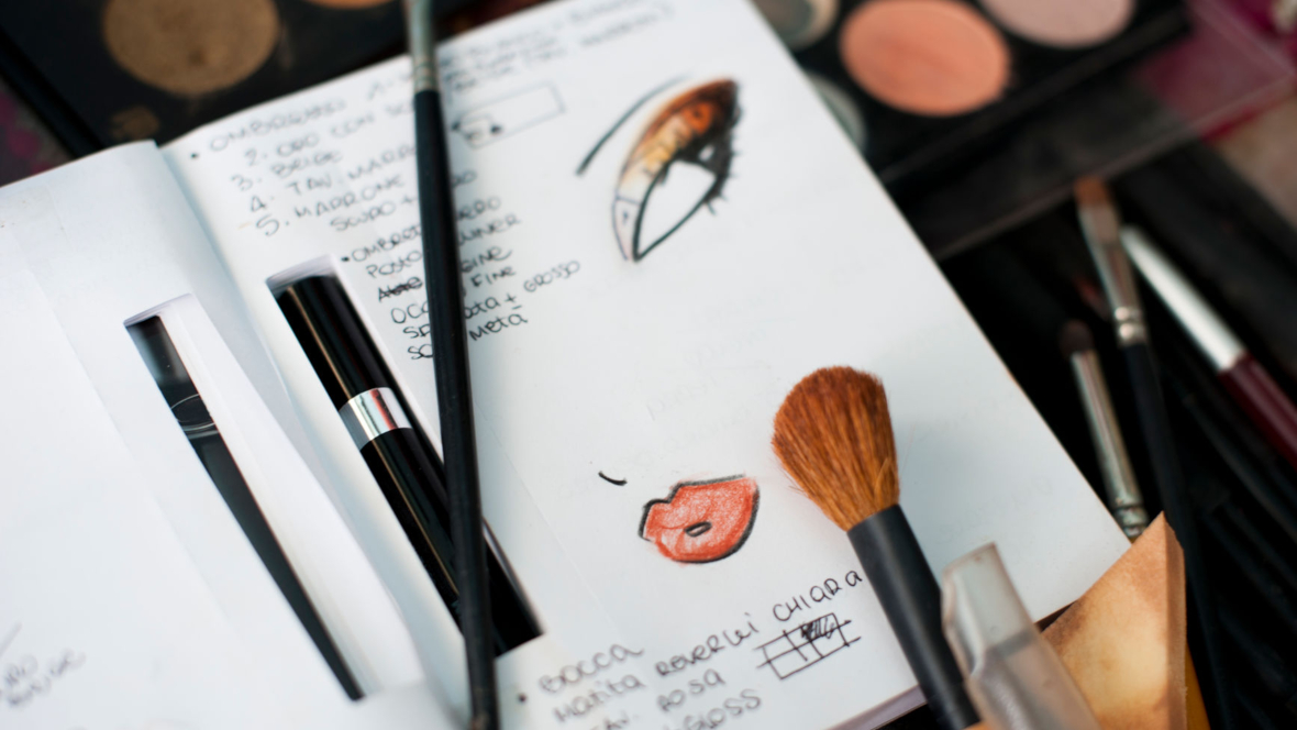 Skizzenbuch mit Make-up-Look, auf dem Make-up-Pinsel liegen