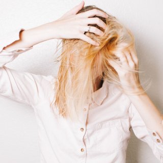 Frau mit blonden Haaren kopfüber und Trockenshampoo im Haar
