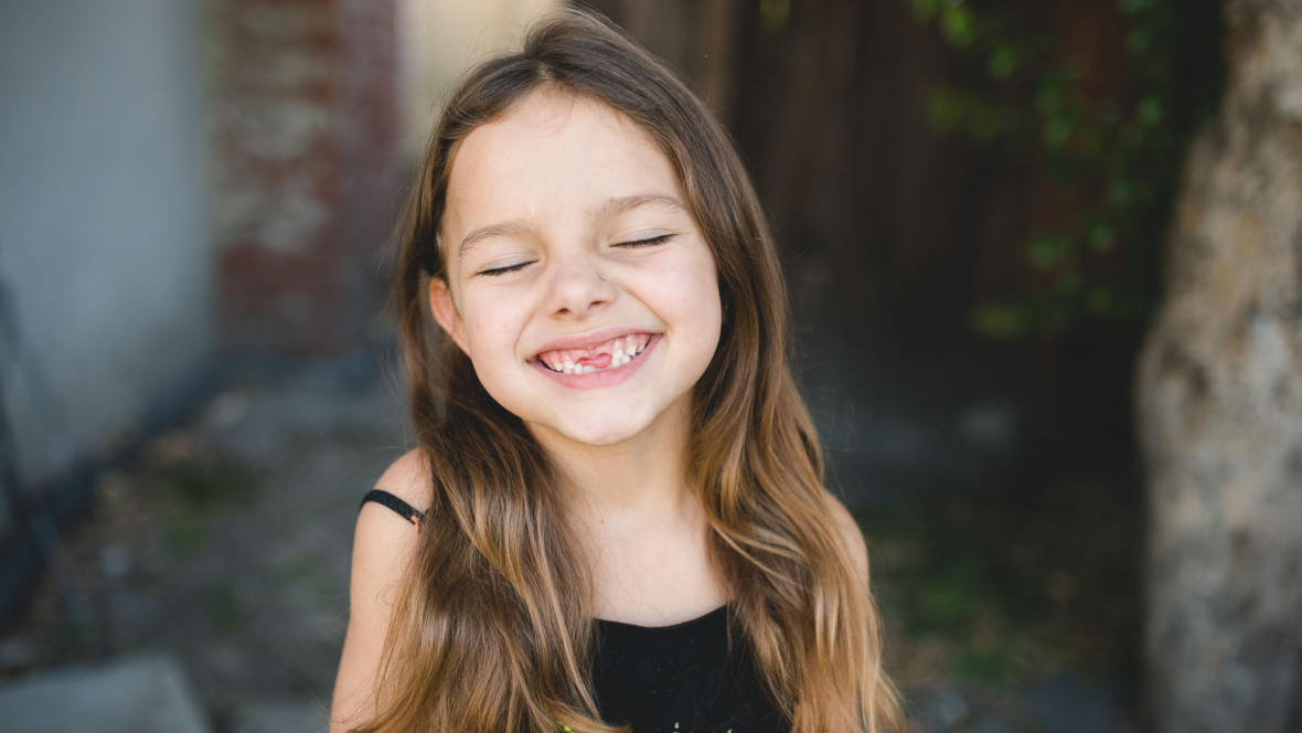 Lachendes kleines Mädchen mit breiten Zahnlücken, die am besten eine elektrische Zahnbürste putzt