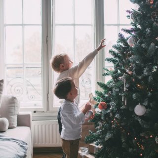 Kinder vor prächtig geschmücktem Christbaum