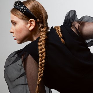 Frau im Seitenprofil mit langem, geflochtenem Zopf und Perlen-Haarreif