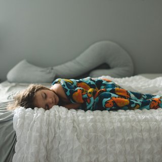 Krankes Kind schläft auf Bett, geschwächt vom Magen-Darm-Virus.