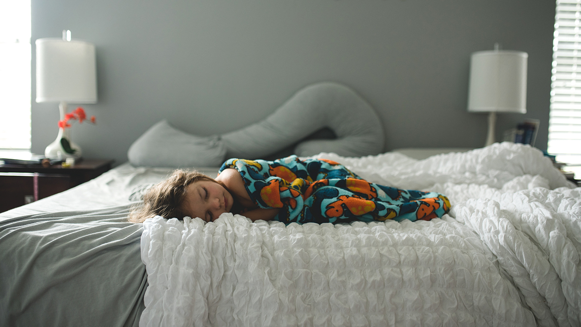 Krankes Kind schläft auf Bett, geschwächt vom Magen-Darm-Virus.