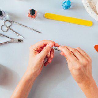 Zwei Hände umgeben von Werkzeug für die Nagelpflege
