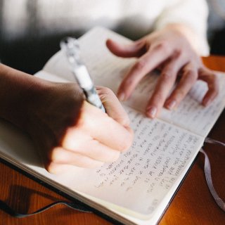 Hände einer Person, die fürs Journaling Tagebuch schreibt
