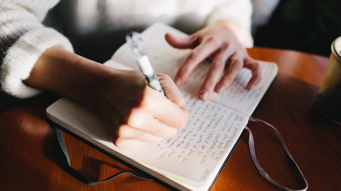 Hände einer Person, die fürs Journaling Tagebuch schreibt