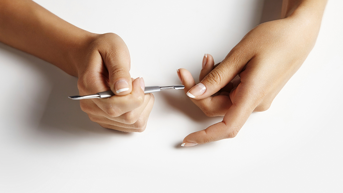 Frauenhände mit Manikürewerkzeug, um Gelnägel selber zu machen.