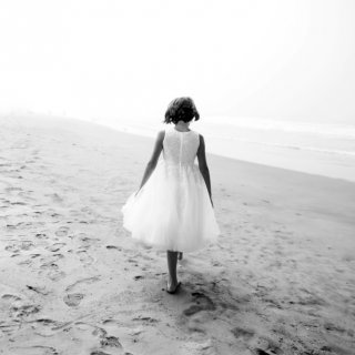 Symbolbild für Sprüche zum Nachdenken: Kind in weißem Kleid am Nebelstrand.