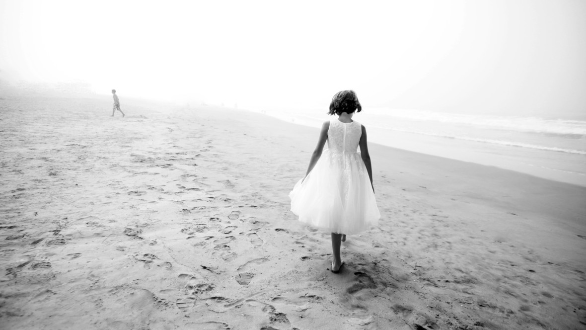Symbolbild für Sprüche zum Nachdenken: Kind in weißem Kleid am Nebelstrand.