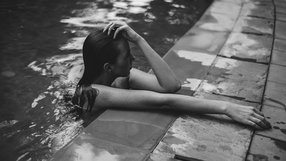 Frau im Pool mit natürlichem Wet-Hair-Look.
