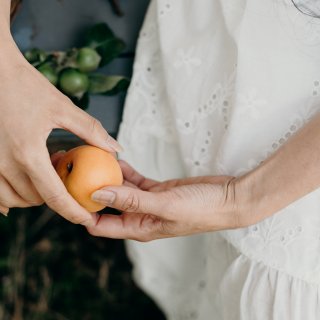 Frau hält frisch gepflückte Aprikose in beiden Händen - für ihren Urlaub zuhause