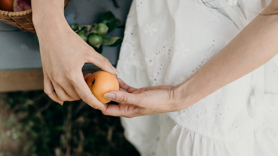 Frau hält frisch gepflückte Aprikose in beiden Händen - für ihren Urlaub zuhause