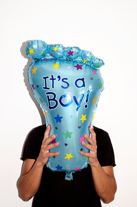 Mann hält blauen Luftballon in Fußform vor sein Gesicht mit der Aufschrift "It's a boy!"