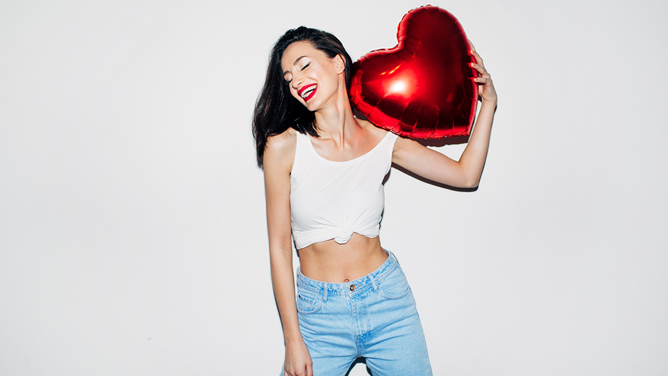 Lachende Frau mit roten Lippen und rotem Herzluftballon