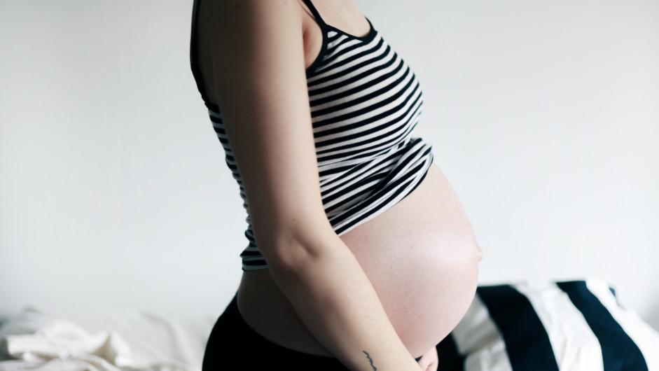 Schwangerschaftswochen - Schwangere Frau mit nacktem Babybauch im Profil