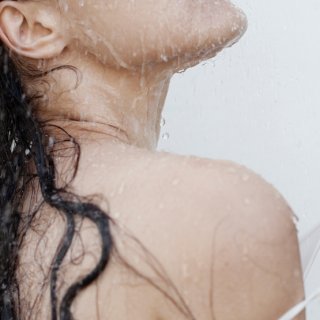 Frau mit nassen Haaren, die sich vielleicht eben fragt, wie oft sie ihre Haare waschen soll.