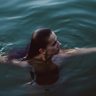 Frau beim Eisbaden in dunkelgrünem Wasser