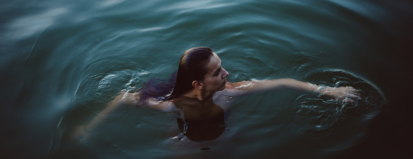 Frau beim Eisbaden in dunkelgrünem Wasser