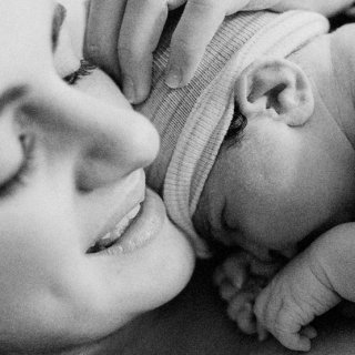 Mutter hält ihr Neugeborenes in Händen - möglicherweise nach einer Kaisergeburt