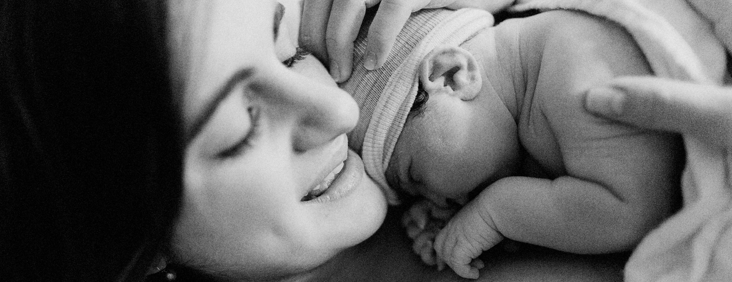 Mutter hält ihr Neugeborenes in Händen - möglicherweise nach einer Kaisergeburt