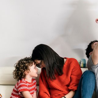 Eltern, die Montessori Tipps anwenden möchten, spielen mit zwei Kindern auf einer Couch