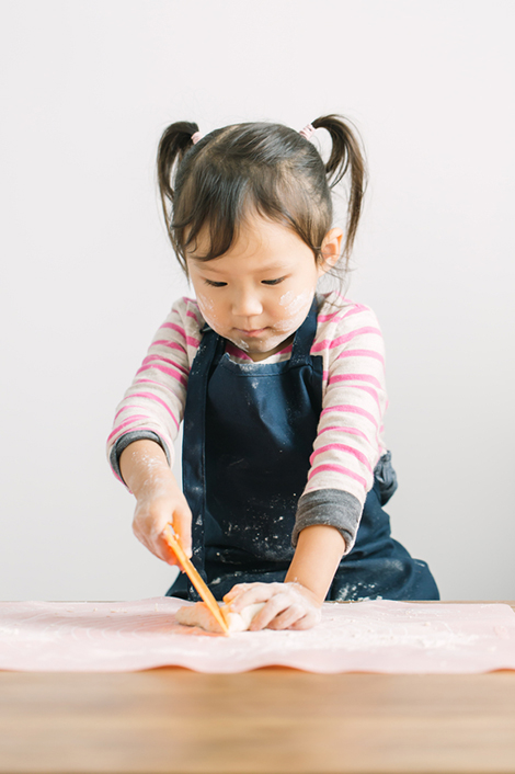 Mädchen knetet Teig - ihre Eltern folgen dem Montessori Grundsatz "Hilf mir, es selbst zu tun"