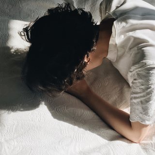 Frau liegt mit dem Gesicht nach unten am Bett - sie leidet unter einer Winterdepression