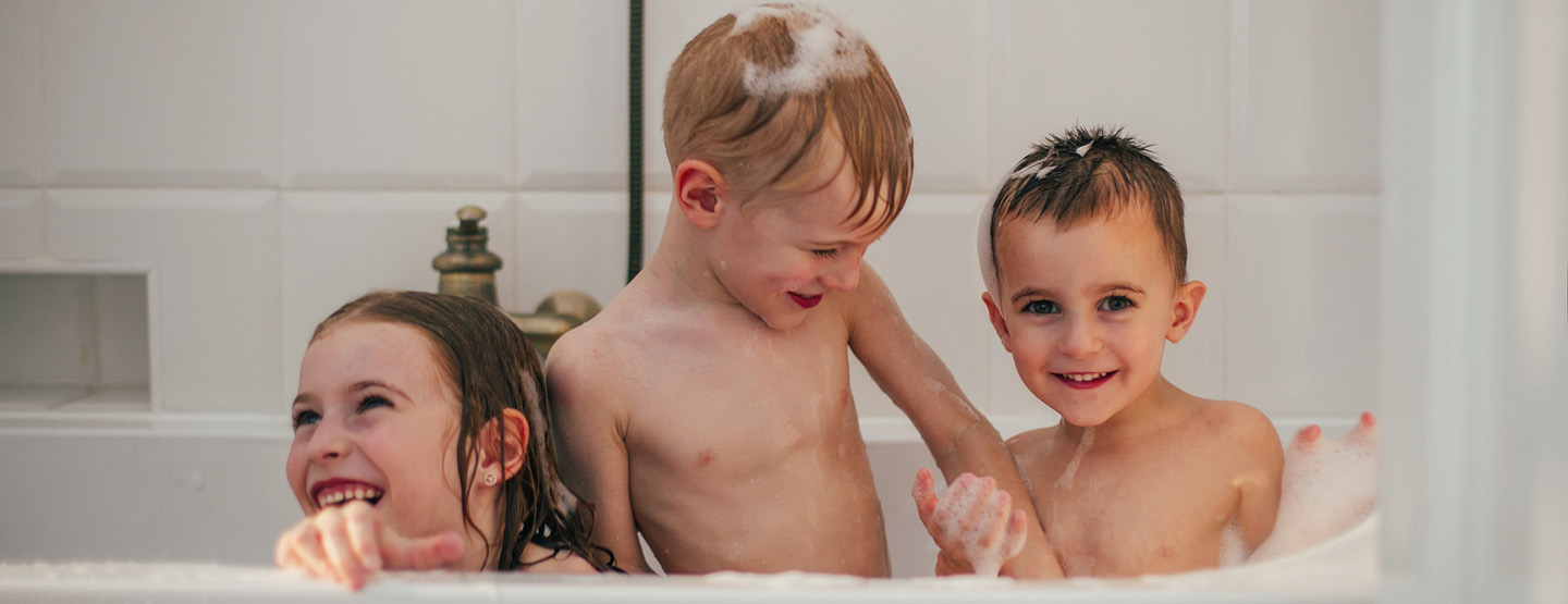 Drei Kinder lachend in der Badewanne