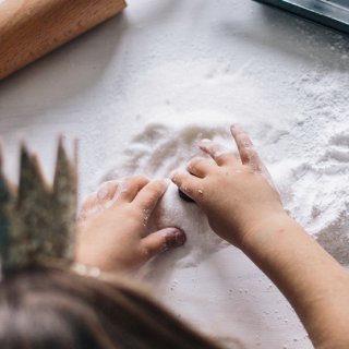 Beim Keksebacken hantieren Kinderhände mit Mehl am Tisch