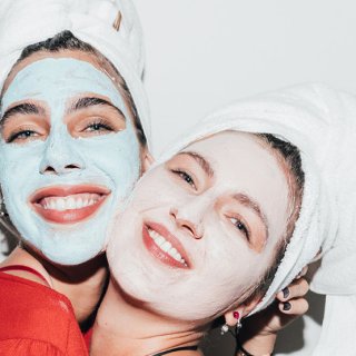 Zwei Frauen mit Gesichtsmaske und Handtuch im Haar fühlen sich schön