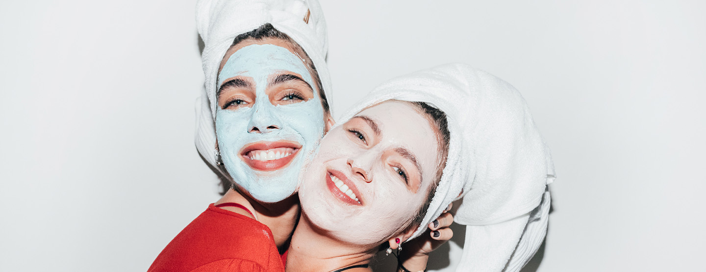 Zwei Frauen mit Gesichtsmaske und Handtuch im Haar fühlen sich schön