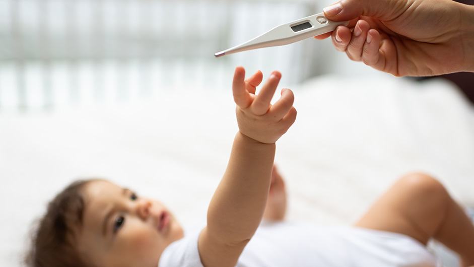 Baby greift nach Fieberthermometer