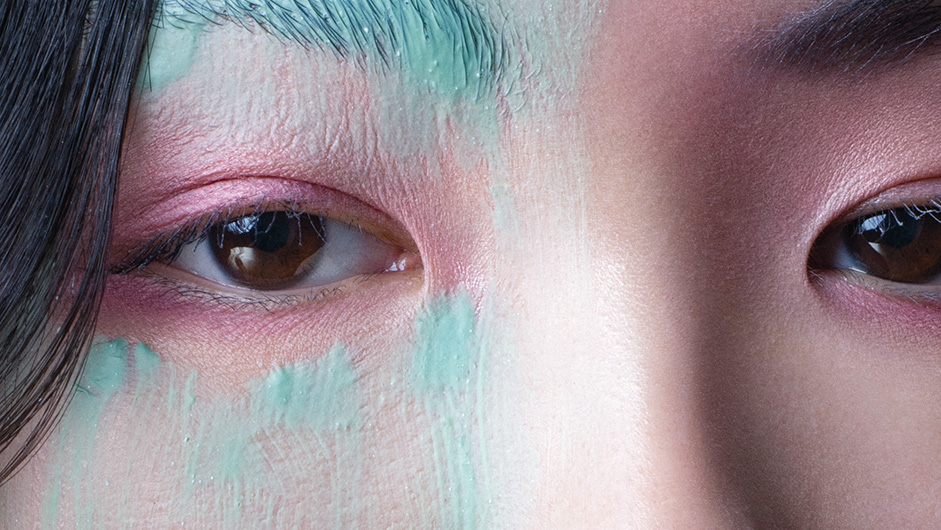 Asiatische Augen mit rosa Lidschatten und grüner Farbe um die Augenpartie