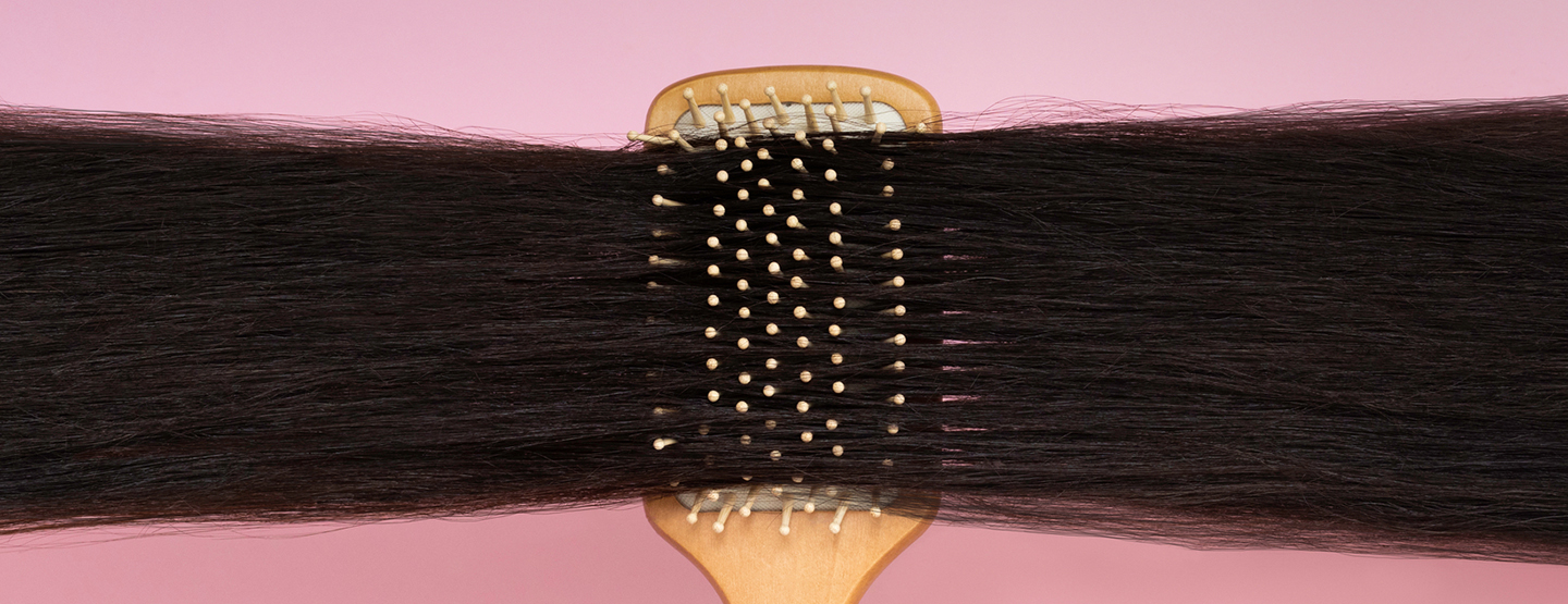 Holzhaarbürste mit der lange, dunkle Haare frisiert werden
