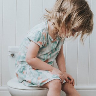 Kleinkind mit Bauchschmerzen sitzt auf der Toilette
