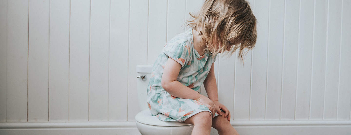 Kleinkind mit Bauchschmerzen sitzt auf der Toilette