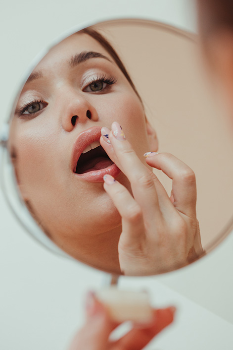 Spiegelbild einer Frau, die sich die Lippen schminkt