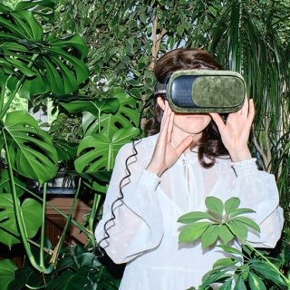 Frau, umringt von Grünpflanzen, blickt durch VR-Brille