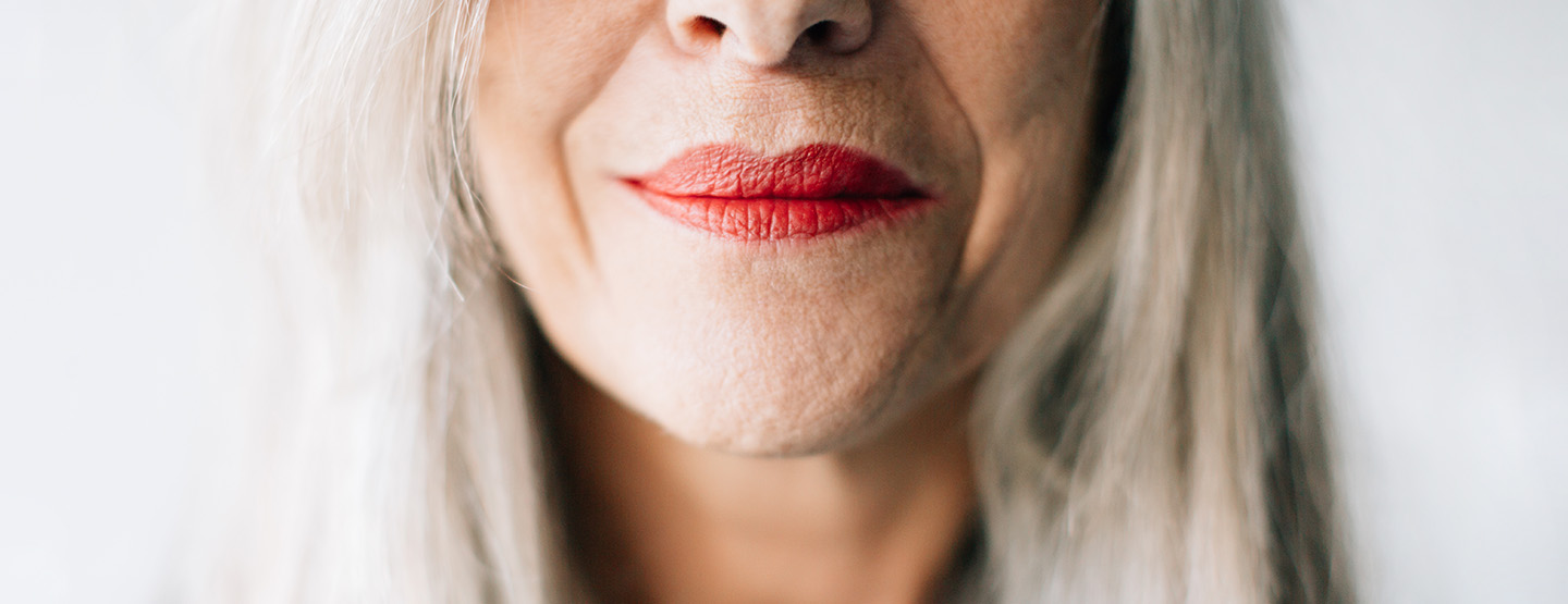 Nahaufnahme eines rot geschminkten Munds mit sichtbarer Hautalterung
